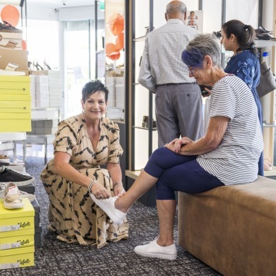 Lady trying on shoes, assisted by female retail worker